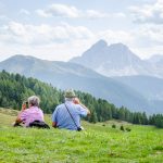 Seniorenpärchen auf der Alm blickt zum Peitlerkofel