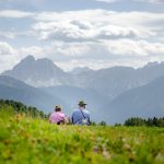 Seniorenpärchen auf der Alm blickt zum Peitlerkofel