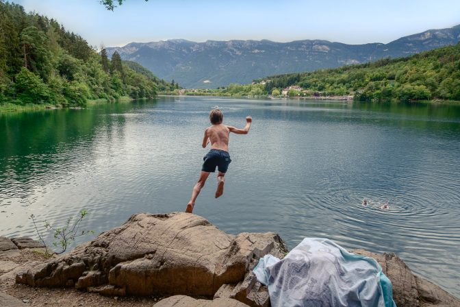 Ganz Mutige springen vom großen Felsen am Nordufer des großen Sees ins Wasser