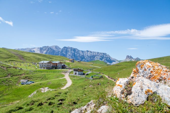 Die Plattkofel-Hütte mit dem Rosengarten im Hintergrund. Ganz rechts strecken sich die Roßzähne gen Himmel.