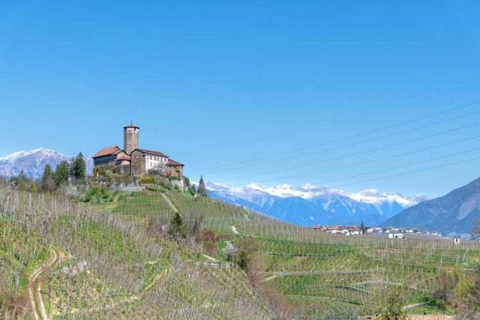 Die Burg Castel Valer mit den weißen Berggipfeln des Ilmenkammes im Hintergrund