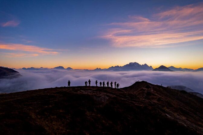 Bergfotografen auf der Punta di Zonia am Passo di Giau. Nebel und Abendrot über den Dolomiten rund um die Marmolata.