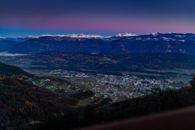 Die Sonne ist längst untergegangen da wir über die Mendelstraße nach Kaltern (im Bild) hinunter fahren. Die Dolomiten erstrahlen nun in rosa und lila Tönen.