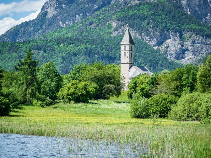 Der Fennberger See mit dem St. Leonhard Kirchlein und der Wiggerspitze mit Teleobjektiv